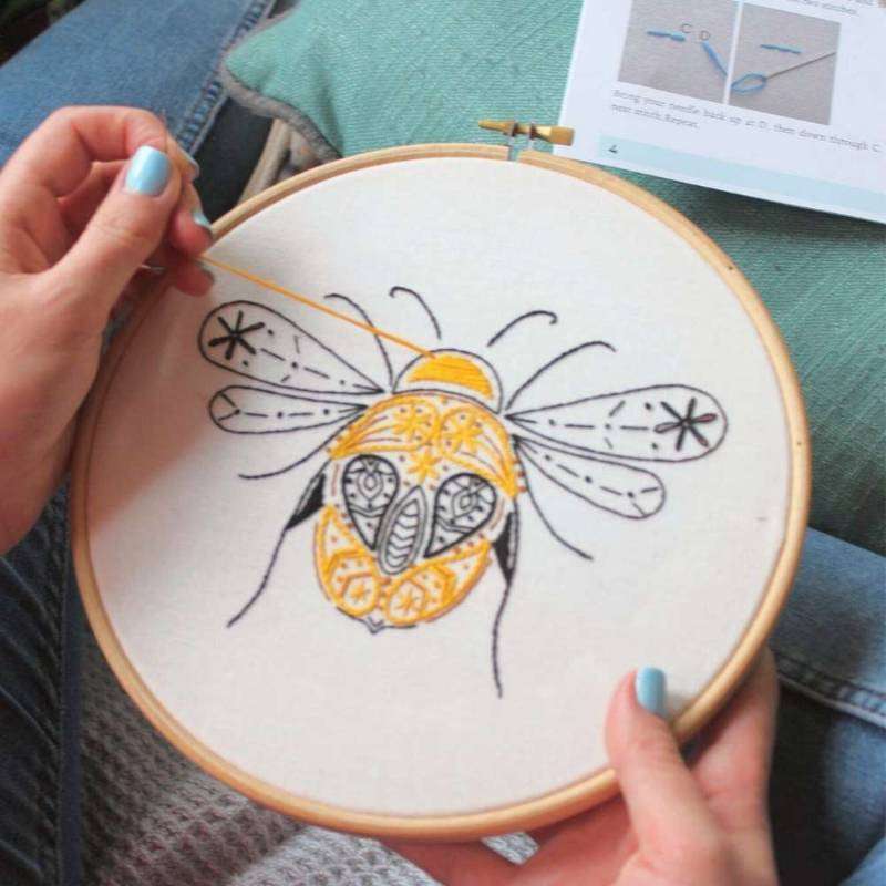 Bee embroidery kit being sewn on sofa