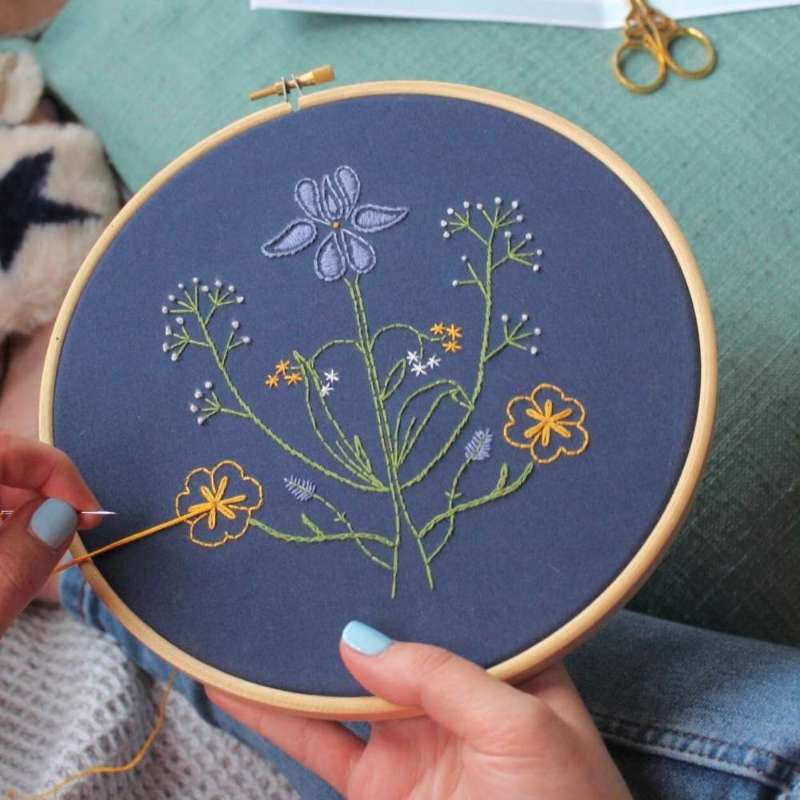 Botanicals embroidery kit held in hands with scissors in background