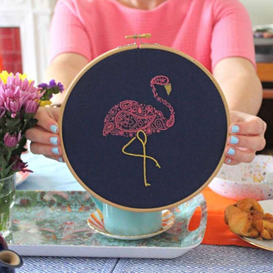 Pink Flamingo embroidery kit held in hands on navy fabric