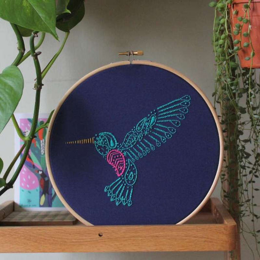 Paisley hummingbird embroidery design in green and pink thread on navy fabric