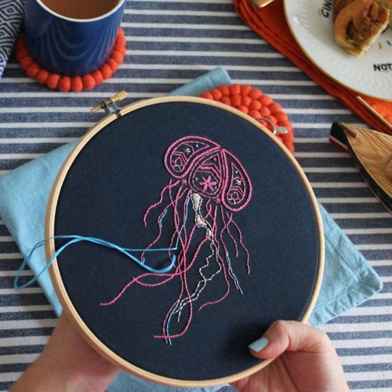 Completed paisley jellyfish embroidery design from embroidery kit held in hands on table