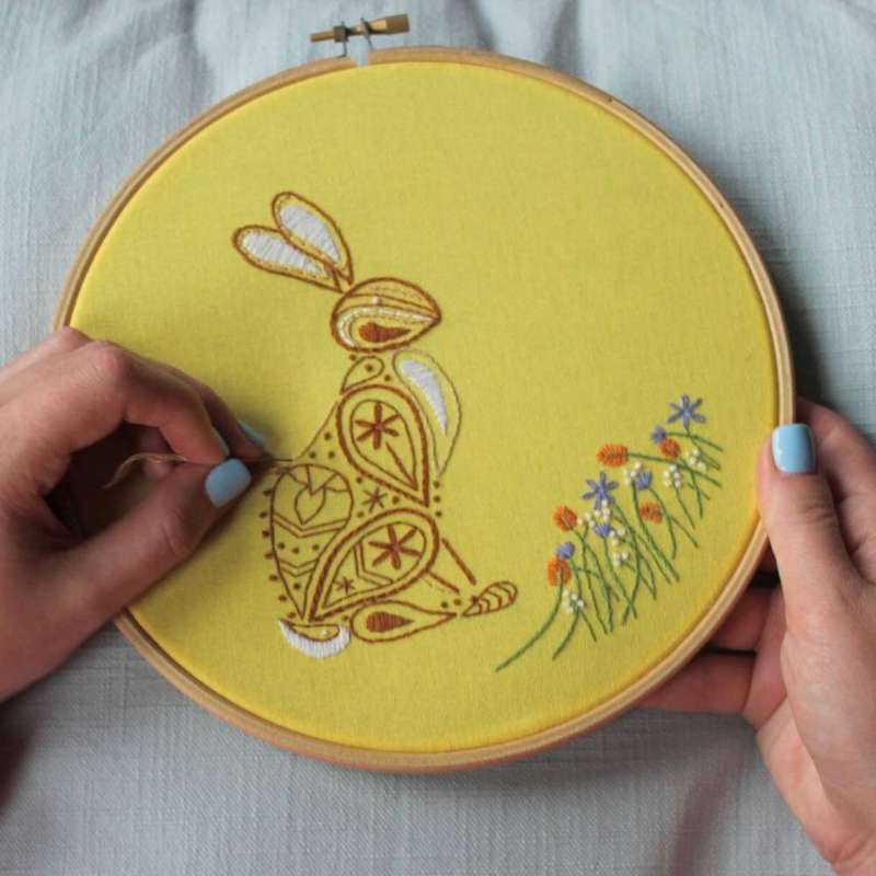 a paisley embroidered rabbit on yellow fabric held in hands