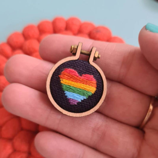 A rainbow heart stitched into fabric in a charm