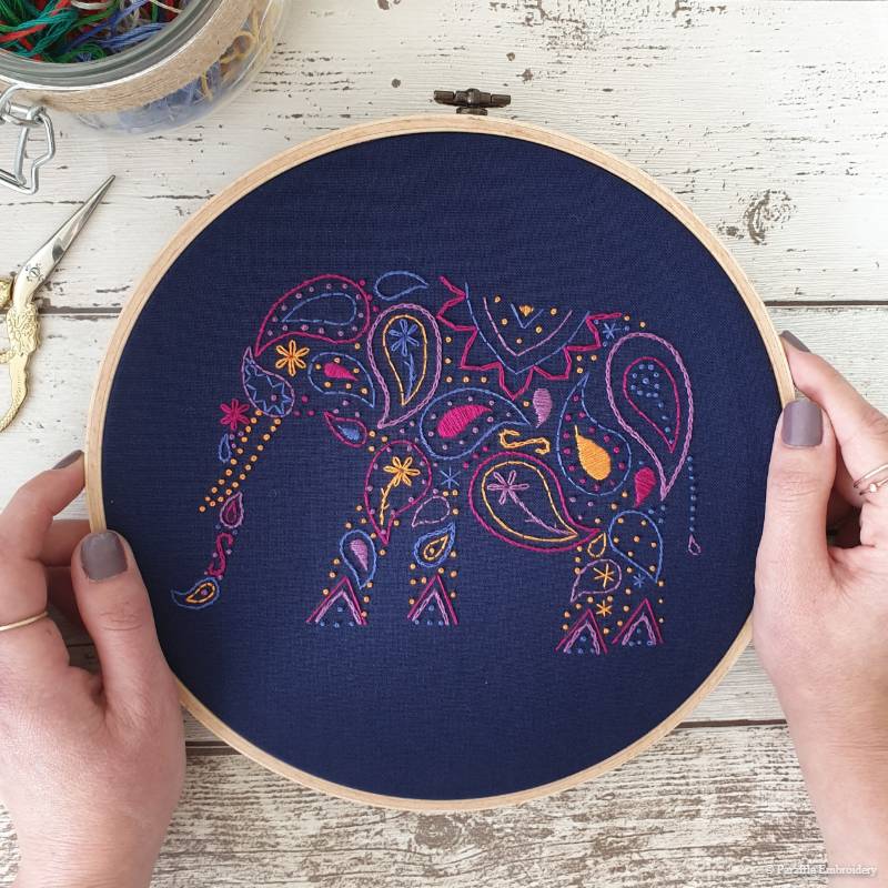 Detail view of paisley elephant embroidery kit on navy fabric in wooden hoop