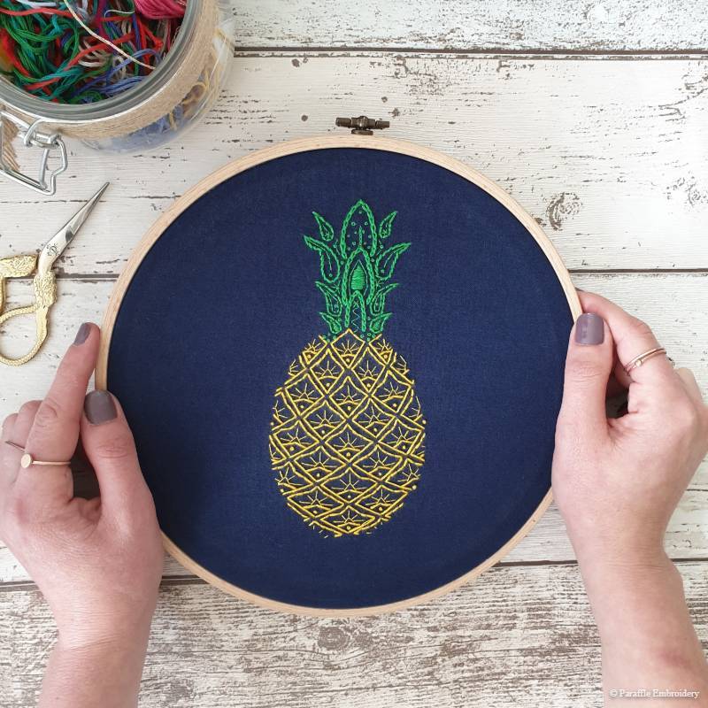 Detail view of paisley pineapple hand embroidery on navy fabric