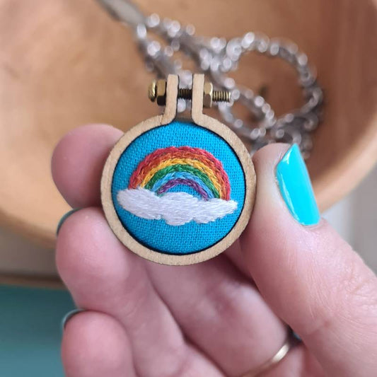 A rainbow stitched into sky blue fabric in a charm